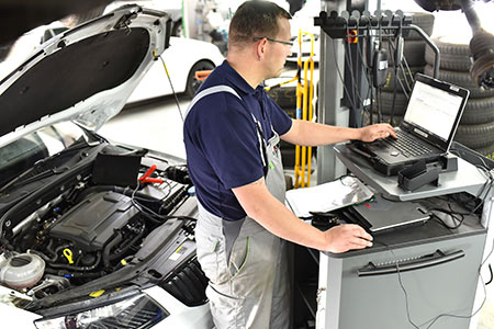 Car mechanic maintains a vehicle with the help of a diagnostic computer
